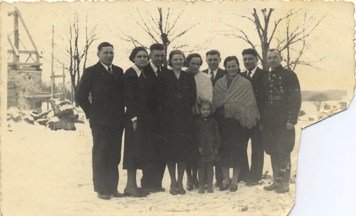 family standing in snow next to building site